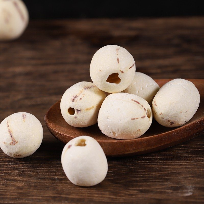 Dried lotus seeds arranged on a wooden tray
